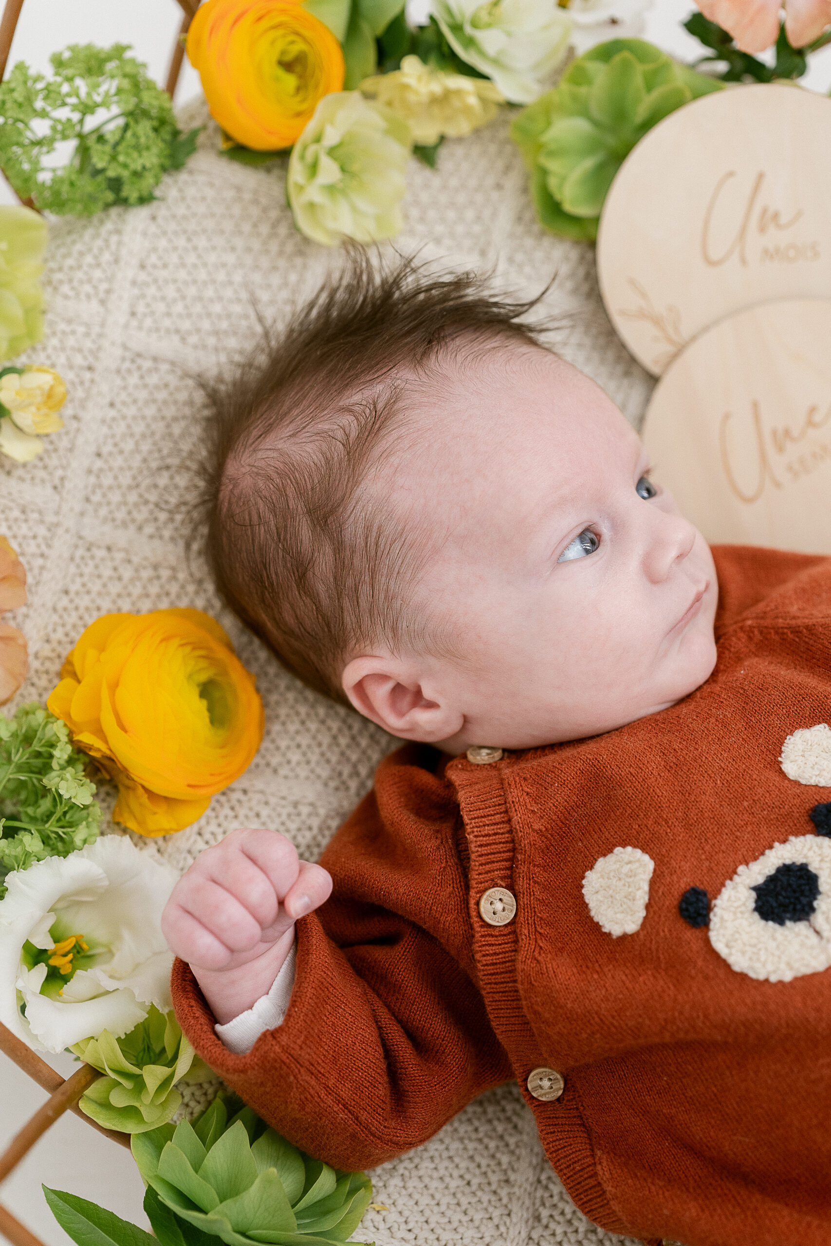 Photographe naissance Reims – bébé Raphaël allongé sur le dos dans un panier fleuri