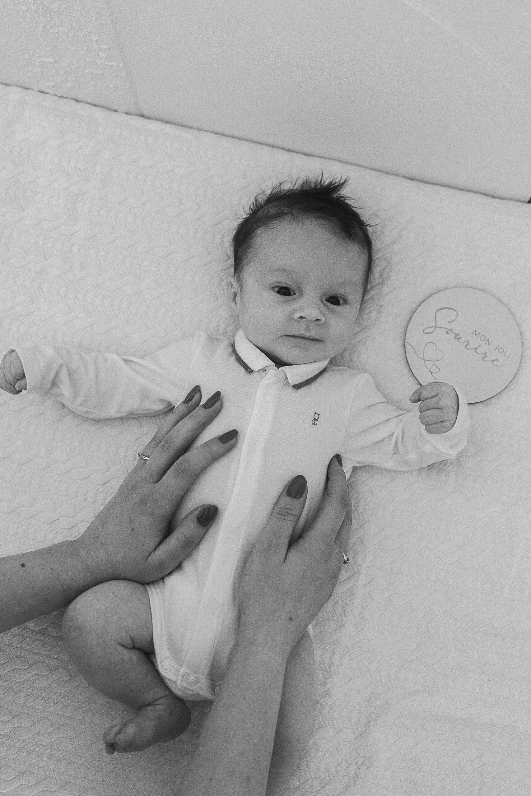 Photographe naissance Reims – bébé allongé sur une couverture, sa maman à ses mains posées sur son ventre